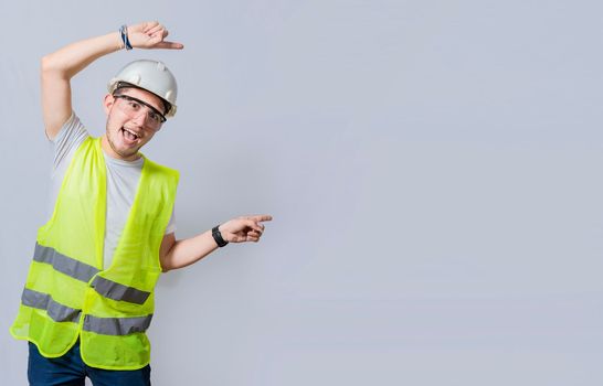 Construction engineer with vest pointing at an advertisement. Engineer man pointing to side. Smiling engineer man pointing aside, Builder engineer pointing finger to the right isolated
