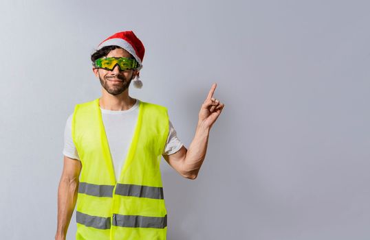 Builder worker with christmas hat pointing a finger at a promotion. Builder engineer in christmas hat pointing to the right, Construction worker with christmas hat pointing to an advertisement
