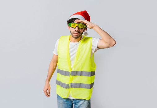 Engineer in christmas hat looking at something in the distance. Engineer in a vest and christmas hat looking into the distance. Builder man in a vest and christmas hat looking into the distance