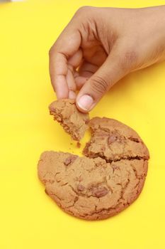 overhead view of breaking sweet cookies on yellow background 
