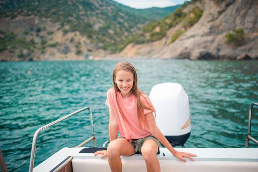 Adorable girl sailing on boat in clear open sea on summer vacation