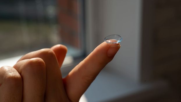 Close-up of a contact lens on a woman's index finger.