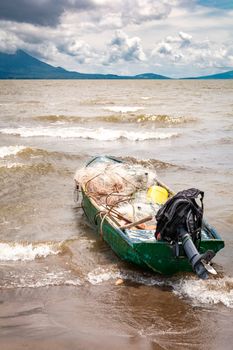 A fishing boat on the shore of a lake with volcanoes in the background. A fishing boat on a lake in Nicaragua. Concept of fishing boats parked at the seaside, Fishing boat on the shore of a lake
