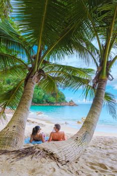 Couple of men and women relaxing at Banana beach with palm trees in Phuket Thailand
