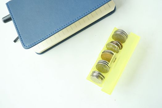 top view of coins in a plastic box on white background 