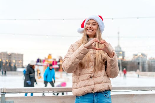 Outdoor portrait young beautiful fashionable woman wearing Santa hat, posing street of European city. Winter Christmas holidays concept.