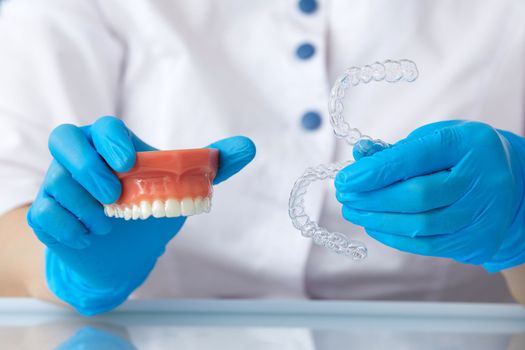 Orthodontist showing the system of aligners on artificial jaws