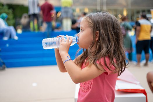Child drink water from plastic bottle outdoor