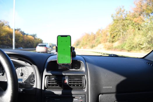 Smartphone with green screen in windshield holder in the car for navigation 