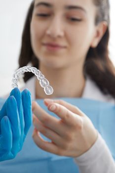 Dentist holdind orthodontic transparent silicone trainer or an aligner for teeth correction