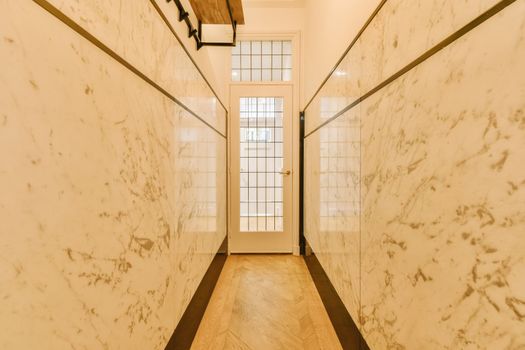 the hallway has marble walls and floors and a door