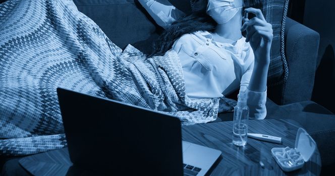 young woman on sofa covered with a blanket freezing blowing running nose got fever, caught, sick girl having influenza symptoms, flu or virus concept
