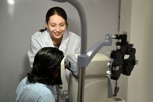 Caucasian female ophthalmologist using special medical device with high precision for examination eye of patient