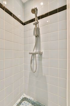 a shower in a white tiled bathroom with a