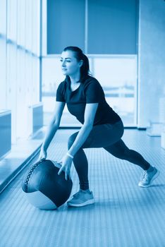 woman in gym relaxing with medicine ball