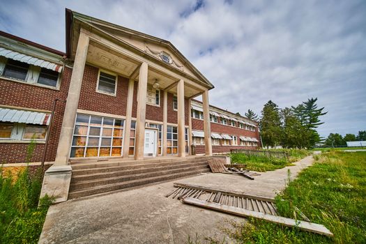 Pillars and steps mark entrance to huge abandoned hospital building in midwest America