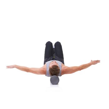 Balance and poise. A young man lying on a foam roller with his arms outstretched - isolated.