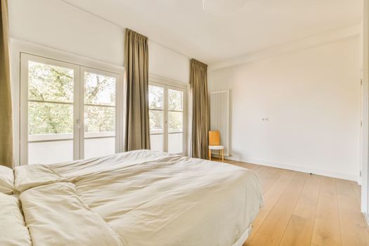 the master bedroom has a large bed and large windows