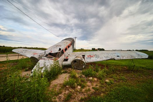 Crashed airplane sets in fields with overcast clouds