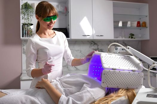 Young woman having photodynamic therapy in beauty salon