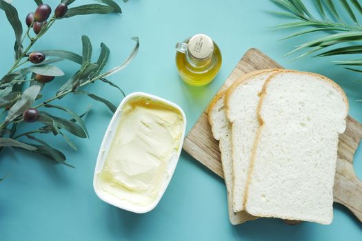 fresh olive butter in a container with bread on table 