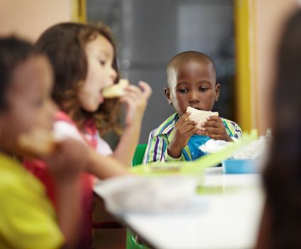 Enjoying a nutritious lunch. Pre-school children on their lunch break eating sandwiches.