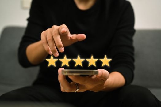 Man using smart phone and giving positive review satisfaction surveys, giving a five star rating.