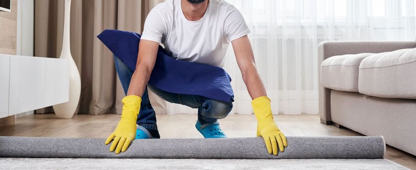 Close up of man unrolling carpet. Cleaning service concept