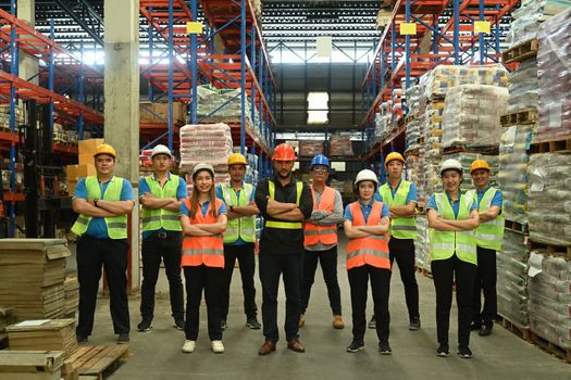 Group of warehouse worker standing in line with arms crossed together at logistic distribution warehouse. Corporate team concept