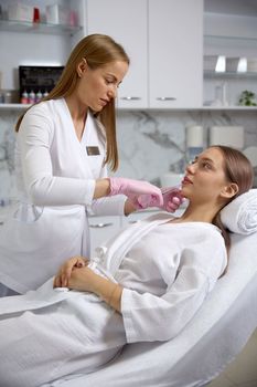 Cosmetologist making the rejuvenating facial injections procedure for tightening and smoothing wrinkles on female face