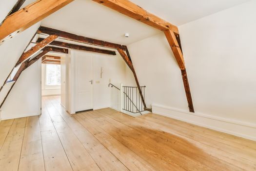 a renovated attic with white walls and wooden beams