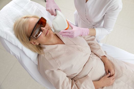 Woman receiving laser treatment in modern cosmetology clinic