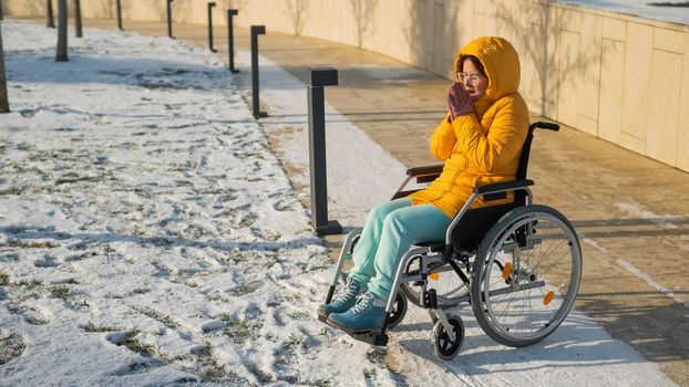 Woman in wheelchair getting cold in winter park.
