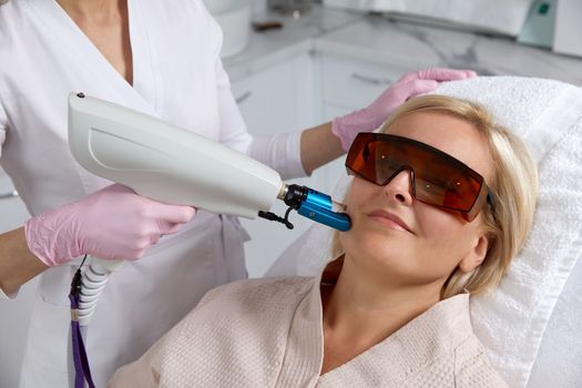Woman receiving laser treatment in modern cosmetology clinic