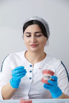 Dentist showing model of human jaw with wire braces and aligners to compare