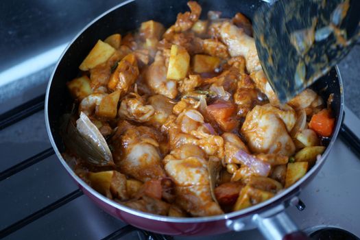 cooking chicken curry in a cooking pan 