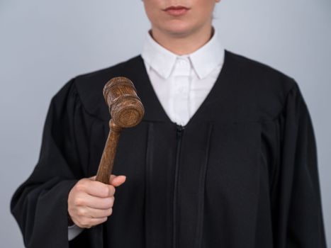 Faceless female judge in a robe holding a court gavel.