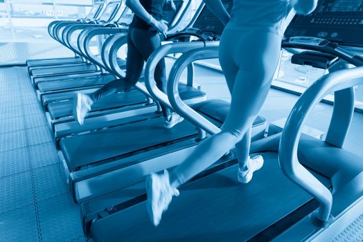 Two young women running on treadmill in gym