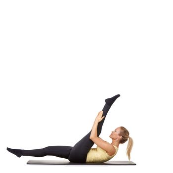 Flexible fitness. A fit young woman stretching out her legs on an exercise mat - isolated.