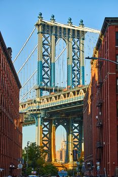 Sunny Manhattan Bridge from Brooklyn New York City between two brick buildings