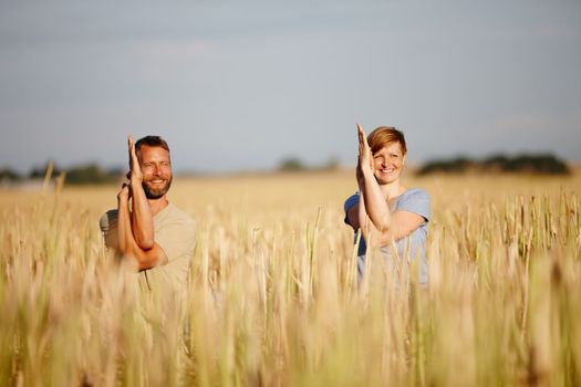 Staying calm as a couple. a serene couple enjoying a yoga workout in a crop field.