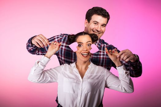 Couple in studio with two pink hearts beeing silly
