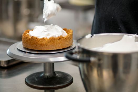 pastry chef designer filling a pie crust with lemon flavour meringue mousse cheese cream with spatula