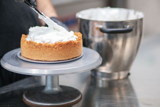 pastry chef designer filling a pie crust with lemon flavour meringue mousse cheese cream with spatula