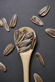 sunflower seeds on wooden spoon on black background 