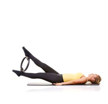 Exercise equipment that actually works. A pretty young blonde working her legs out with a pilates ring.