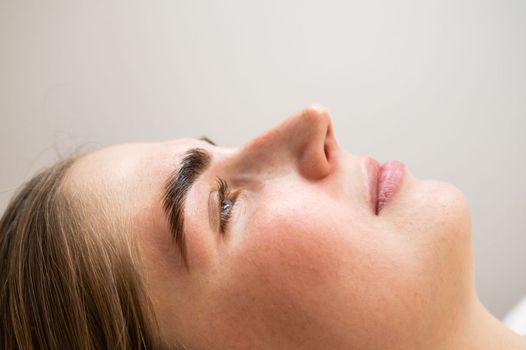 Close-up portrait of a woman after the procedure of correction and lamination of eyebrows.