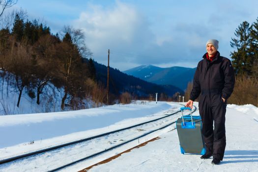 man in winter clothes standing on the platform of a train station