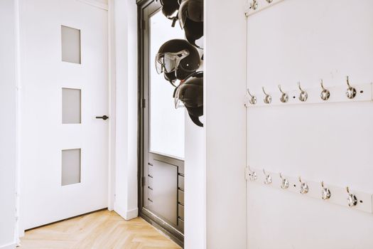 a hallway with white walls and a closet with helmets
