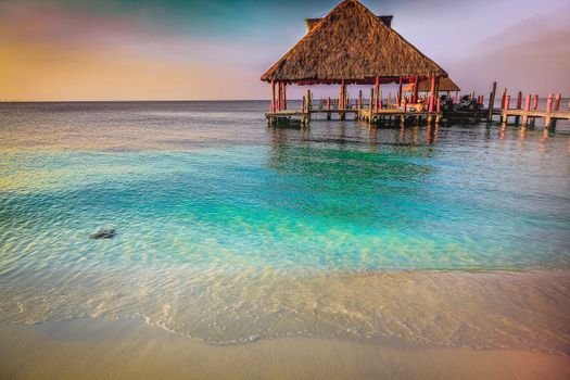 Tropical paradise, sand beach in caribbean with palapa and pier, Cancun, Mexico